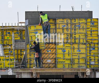 Construction builders assembling yellow Doka formwork panels for a concrete wall on a site in Prague, Czech Republic. Stock Photo
