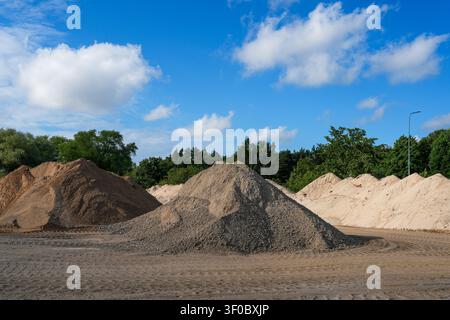 Large stockpiles of sand and gravel at a construction materials yard, ready for concrete production, roadworks and building projects Stock Photo