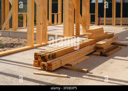 Stacked lumber inside a timber frame house under construction on a concrete slab, ready for framing, interior work and finishing installation Stock Photo