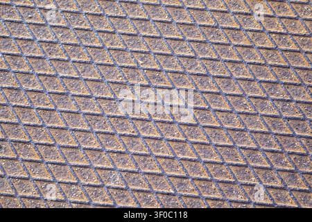 Close-up view of a weathered diamond metal plate with repeating geometric tread pattern. Suitable for industrial backgrounds, construction themes, eng Stock Photo