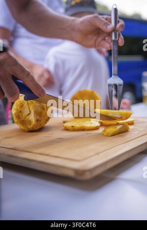 Hands cutting fresh pineapple on a wooden board outdoors, wedding, Grossglattbach, Germany Stock Photo