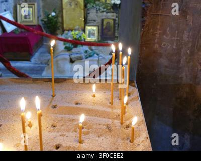 GEORGIA, CAUCASUS - APR 27, 2024 - Burning candles set in sand inside an ancient Georgian Orthodox church, symbolizing prayer, remembrance, faith and Stock Photo