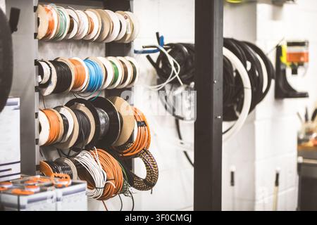 A detailed view of a storage rack displaying numerous spools of electrical wire in different colors and sizes, ready for use in construction or repair Stock Photo
