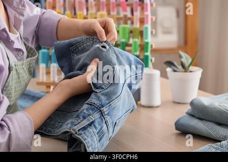 Person repairing hole in denim jacket by hand Stock Photo