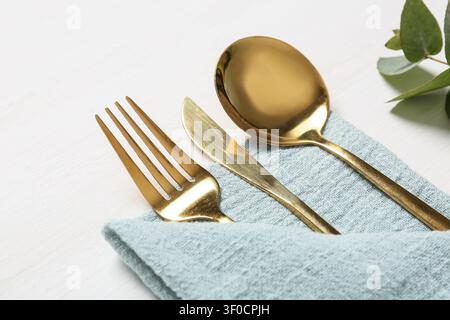 golden cutlery set on blue napkin with green leaves Stock Photo
