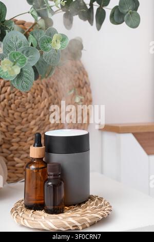 Air humidifier with essential oils and eucalyptus on table in bedroom, closeup Stock Photo