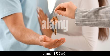 Handing over house key to man with pregnant woman in background Stock Photo