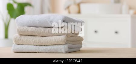 Stack of clean folded towels on wooden table Stock Photo