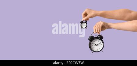 Hands holding two black alarm clocks of different sizes Stock Photo