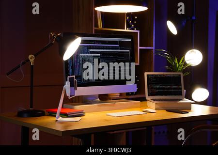 Modern workspace with desktop and laptop displaying code Stock Photo