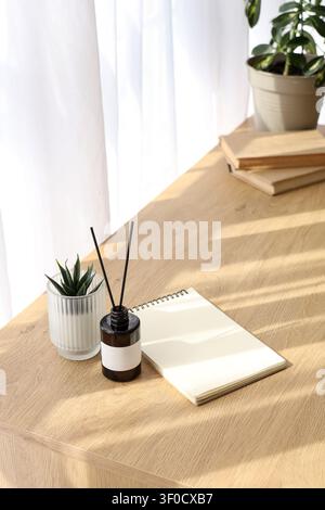 Aroma diffuser, houseplant and notepad on table in room Stock Photo