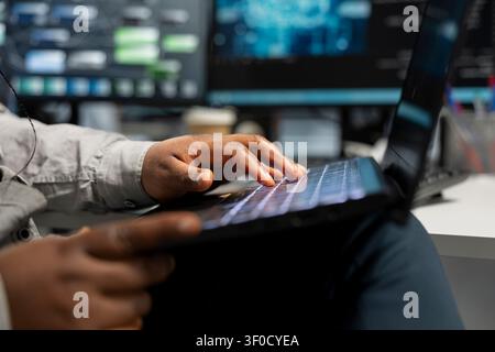 Data center technician uses a laptop to manage machine learning workloads, working with AI technology and high performance systems. Stock Photo