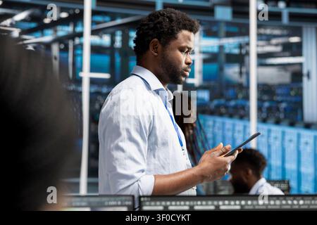Data center team uses a digital tablet in a data center to monitor equipment, manage workflows, and support reliable infrastructure. Stock Photo