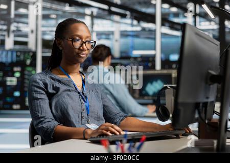 Data center programmer reviews performance analytics on a desktop computer in a data center to optimize storage systems and resource use. Stock Photo