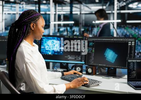 Computing specialist in advanced technology server facility supervising AI training datasets. African American woman supervises ML in data center supporting scalable infrastructure for AI apps. Stock Photo