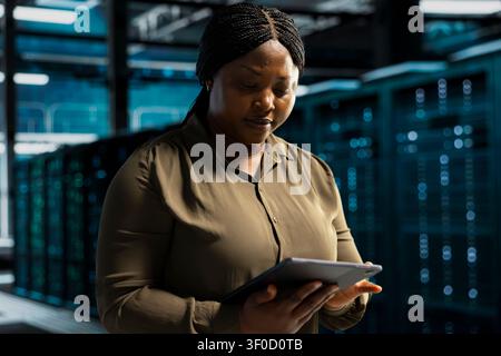 Admin working with device app to do maintenance in server facility with setup helping companies stay connected. Stock Photo