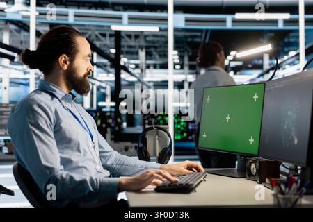 Data center engineer works with a chroma key computer, using an editable screen to update server software. Stock Photo