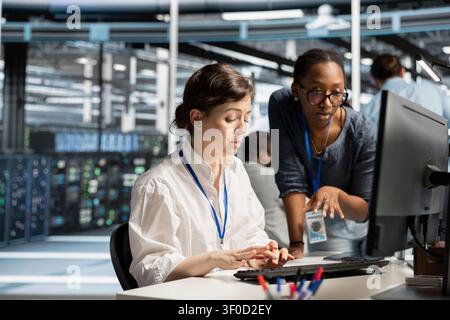 Data center colleagues collaborate on coding and AI automation scripts while reviewing server infrastructure together. Stock Photo
