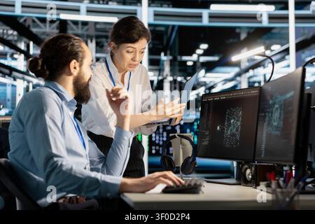 Data center colleagues collaborate on coding and AI automation scripts while reviewing server infrastructure together. Stock Photo