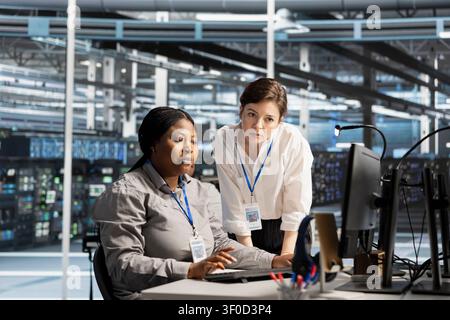Data center colleagues collaborate on technical analysis and server infrastructure management inside a high-tech facility. Stock Photo