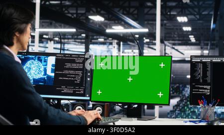 Technician programs on a green screen computer in a data center with generative AI assistance. Stock Photo