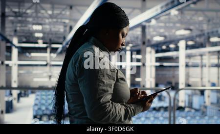 IT expert checks server environment activity working with digital tablet while walking on industrial platform. Stock Photo