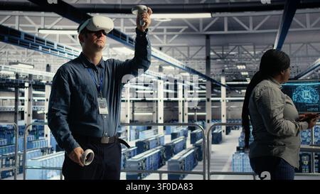 Programmer uses a VR headset in a server room to adjust AI systems and improve processing performance. Stock Photo