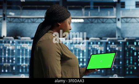 Data center administrator works with a chroma key tablet, using an editable screen to manage technical tasks. Stock Photo