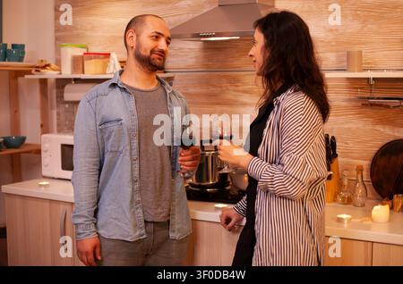 Senior couple having fun during romantic date during a warm domestic meal where tableware, conversation and romantic gestures create a senior lifestyle moment. Stock Photo