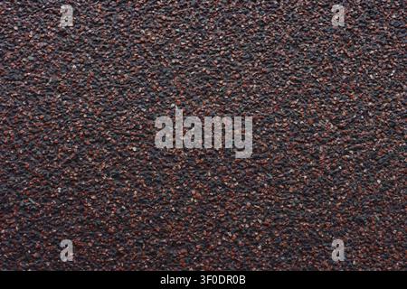 Full frame background of a dark red and black mineral mosaic plaster wall texture. This rough grainy stucco surface with tiny stone chips is perfect f Stock Photo