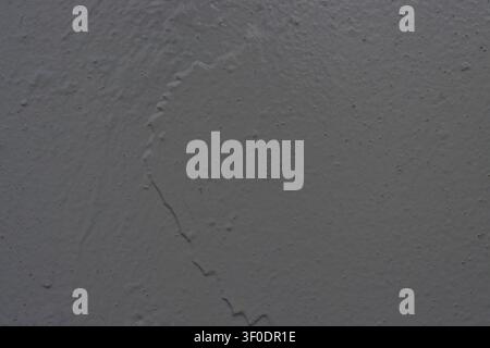 Detailed background texture of a grey concrete wall featuring an uneven plaster surface, painted texture, and a noticeable crack or seam line, perfect Stock Photo