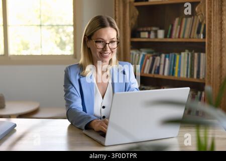Woman working remotely on laptop at home office Stock Photo