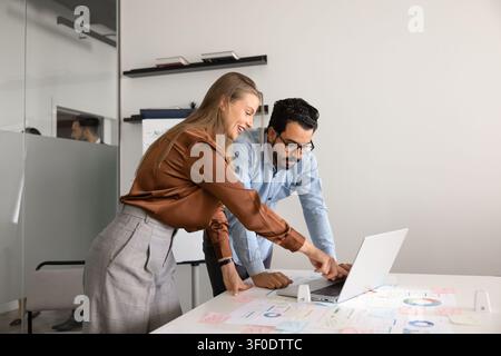 Colleagues reviewing marketing strategy, discussing financial charts working on laptop Stock Photo