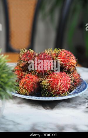 Rambutan fruits piled high on a decorative blue plate Stock Photo