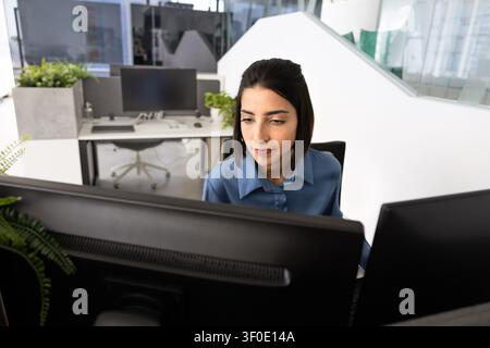 Focused office worker analyzing data on dual monitors Stock Photo