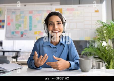 Portrait of businesswoman in headphones leading videoconference using videocall application Stock Photo
