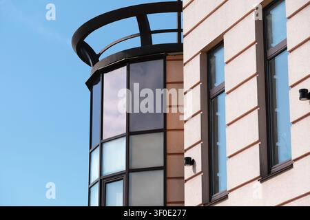 Minimalist view of a modern building facade featuring large glass windows, clean architectural lines, and blue sky with generous copy space for corpor Stock Photo