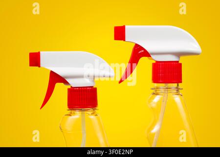 Close-up detergent sprayers on a yellow background. Two red and white sprayers. Stock Photo