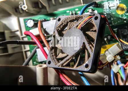 Dusty fan to cool your computer against the background of electronic components. Cleaning and maintenance of electronics. Stock Photo