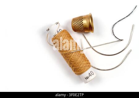 Needle threads and thimble on a white background. Composition of sewing accessories. Stock Photo