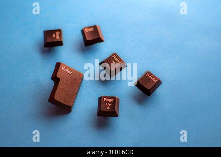 Close-up of detached black keyboard keys including Enter, Delete, Esc, Home, End and Page Up on blue background. Symbolizing technology, typing, and d Stock Photo