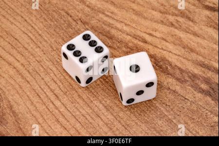 Two white dice showing six and one on wooden surface. Game of chance concept. Symbolizing luck, chance, gambling and probability in games and decision Stock Photo