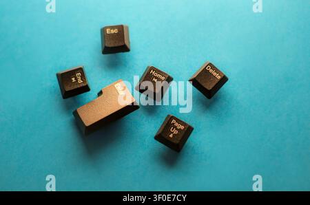 Close-up of scattered black keyboard keys including Enter, Delete, Home, End and Esc on a blue background. Symbolizing technology, computing, digital Stock Photo