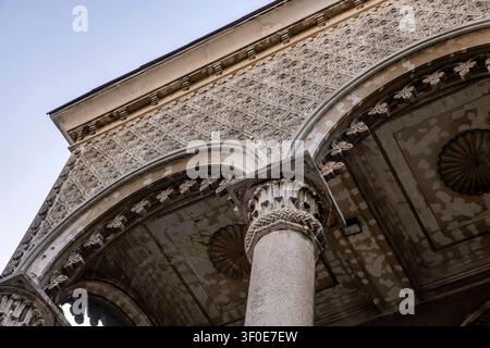 Low-angle view captures the weathered detail of an ornate classical stone column and archway. Featuring intricate bas-relief lattice patterns. Ideal f Stock Photo