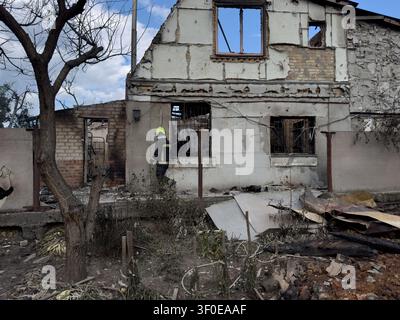 Vyshneve, Kyiv Region, Ukraine July 6, 2026: Emergency service worker stands near heavily damaged residential building after missile attack. Burned st Stock Photo