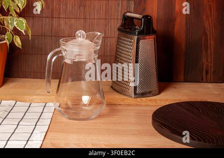 Kitchen still life with grater, pitcher, and cutting board on wooden surface Stock Photo