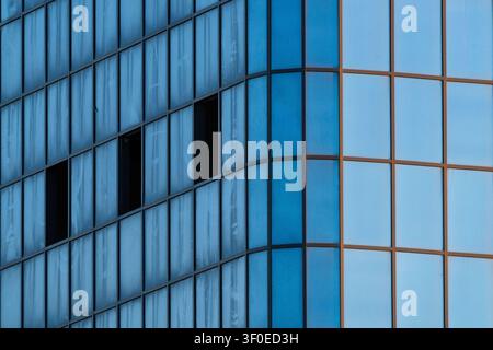 View of the modern glass facade of a building with reflective blue panels and dark window frames in Aktau, Mangystau Region, Kazakhstan. Stock Photo