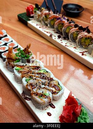 Assorted sushi rolls presented on wooden platters with garnishes of wasabi and pickled ginger Stock Photo