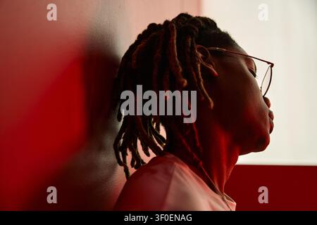 Black Man Leaning Against Wall Conveying Stress and Burnout Stock Photo