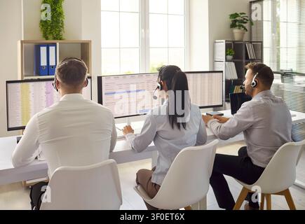 Call center agents with headsets working at computers in modern bright office Stock Photo